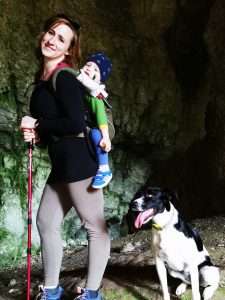 LucaKutya egy barlangban túrázik a gazdájával, akinek a hátán egy kisfiú van hordozóban