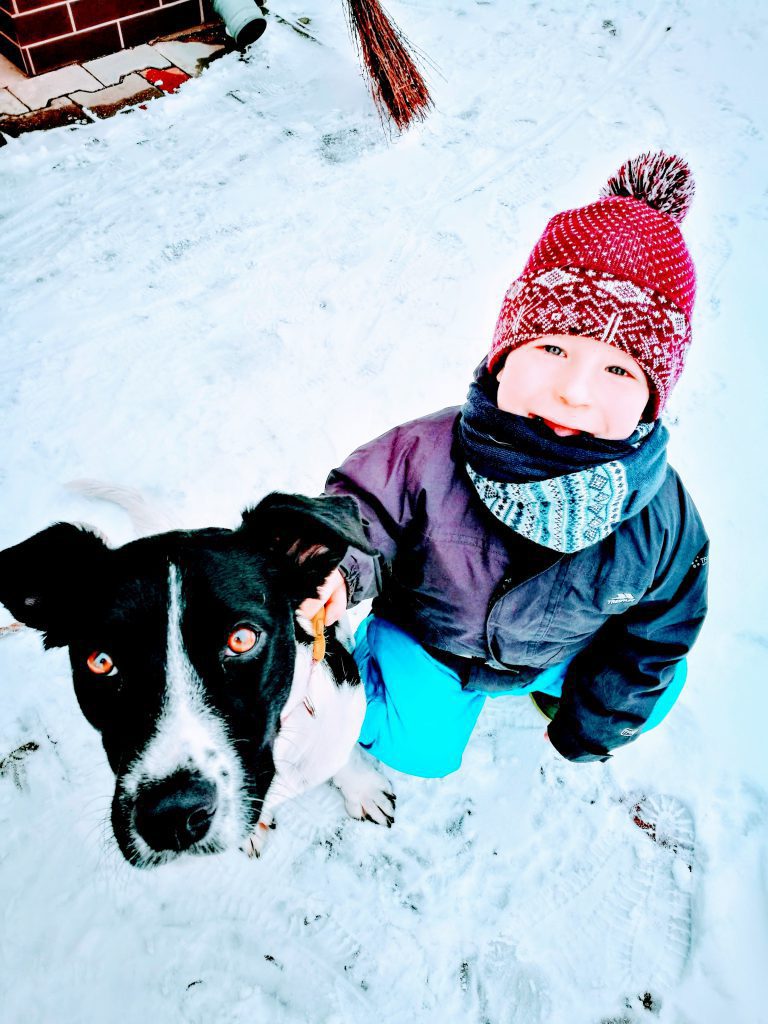 LucaKutya és egy kisfiú ülnek a hóban és a kamerába néznek