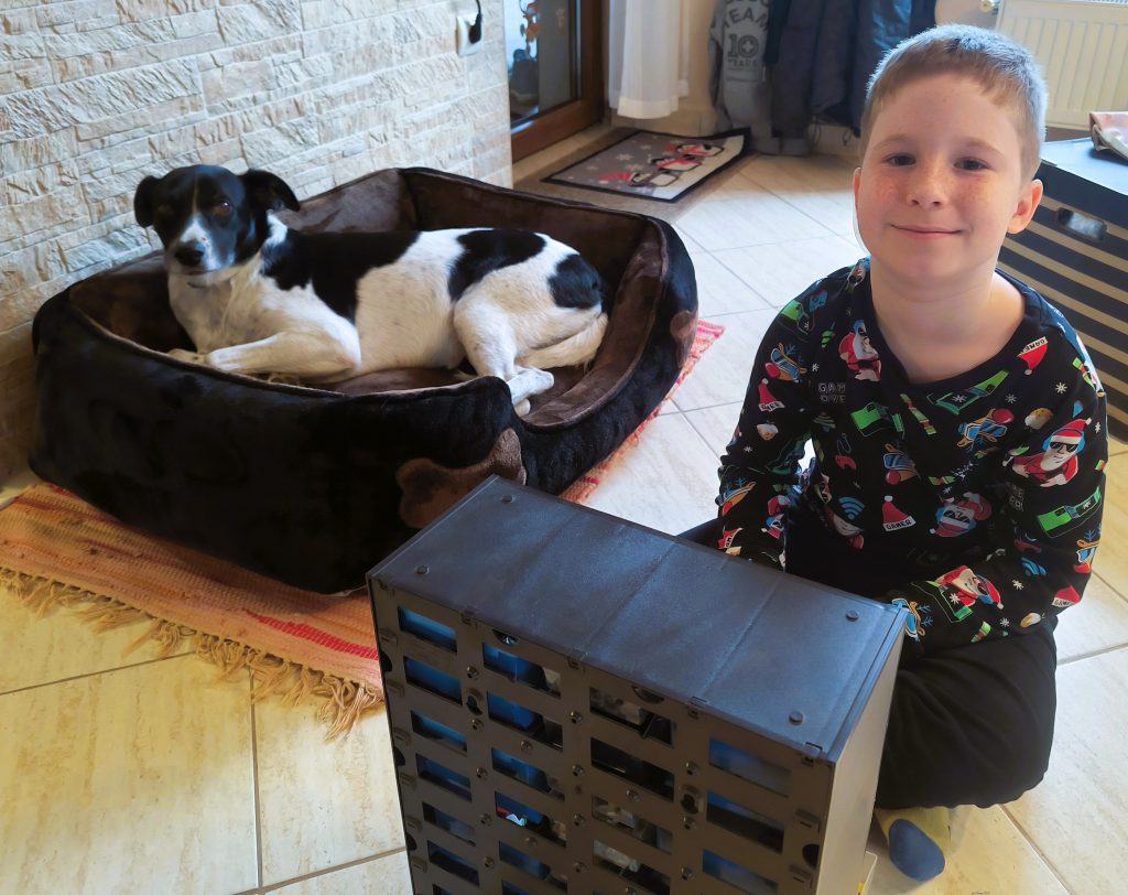 LucaKutya otthon a családdal: Luca az ágyában fekszik mellette egy kisfiú játszik