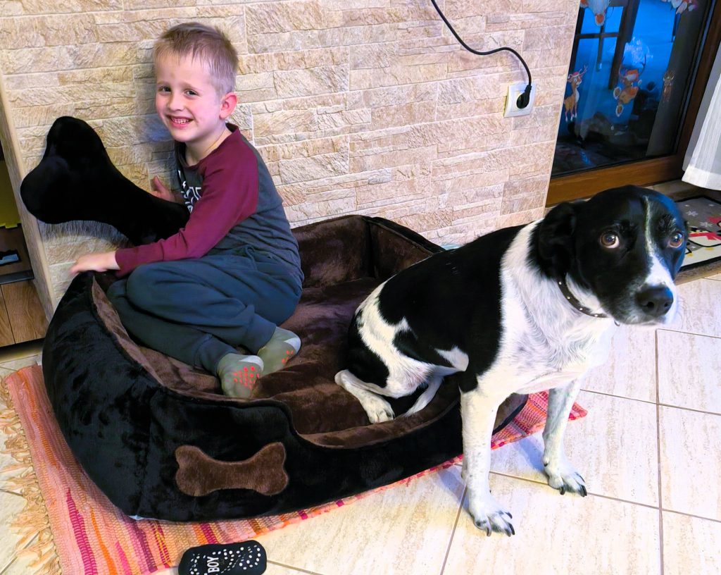 LucaKutya az ágyában fekszik egy nevető kisfiúval.